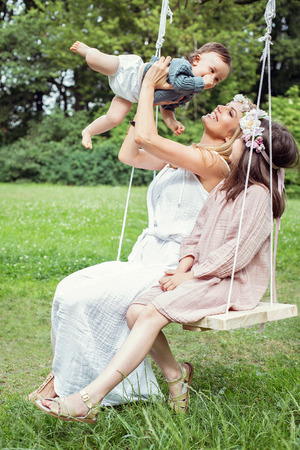 Mother and children sitting on a swingの写真素材