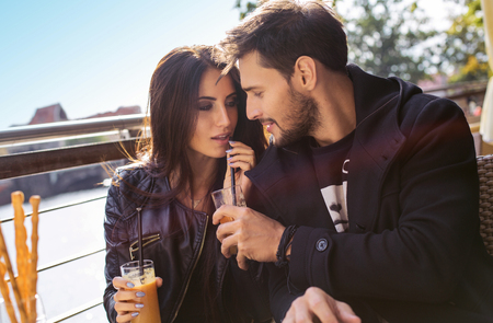Happy couple drinking orange juice in autumn timeの写真素材