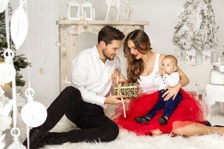 Father giving a christmas present to his wife. Happy familly in Christmass Timeの写真素材