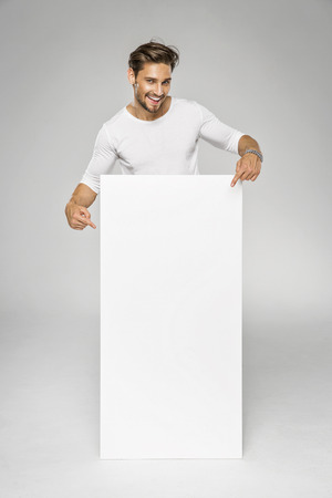 Smiling handsome man showing white empty space for advertの写真素材