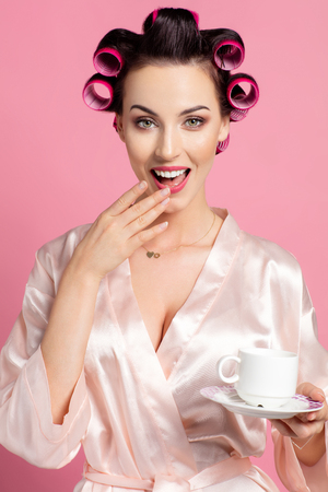 Surprised woman wear robe with hair rollersの写真素材