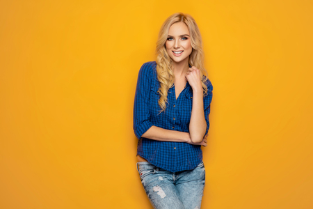 Beautiful smiling woman with clean skin, and white teeth posing on orange backgroundの写真素材