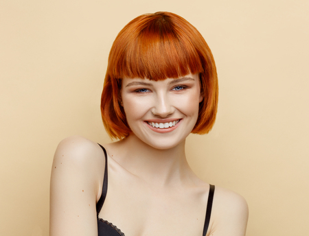 Beauty portrait of smiling female model with red hair and natural skin textureの写真素材