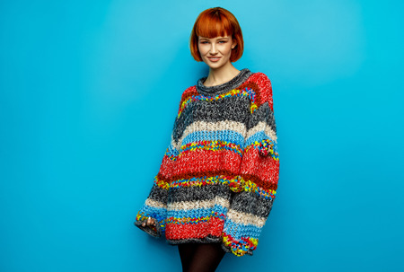 Colorful photo of young female model wear oversize sweater isolated on blue backgroundの写真素材