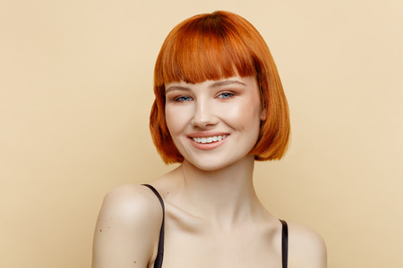 Beauty portrait of smiling female model with red hair and natural skin textureの写真素材