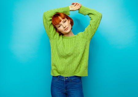 Attractive young fashion woman wear green sweater isolated on blue backgroundの写真素材
