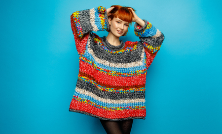 Colorful photo of young smiling female model wear oversize sweater isolated on blue backgroundの写真素材