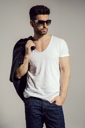 Handsome man holding the jacket in his hand and wearing sunglassesの写真素材