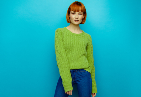 Attractive young fashion woman wear green sweater isolated on blue backgroundの写真素材