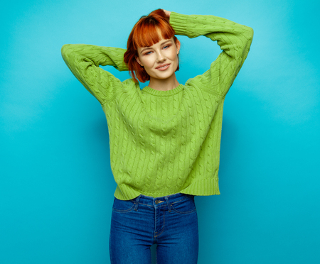 Attractive young fashion woman wear green sweater isolated on blue backgroundの写真素材