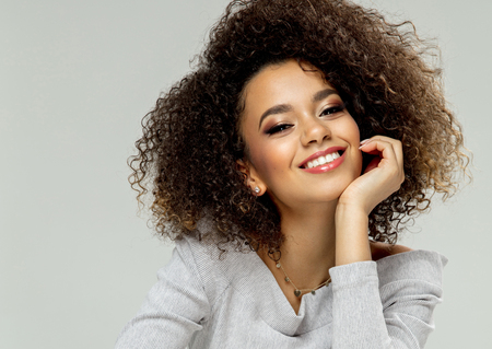 Beauty portrait of young black woman sitting on chair and smilingの写真素材
