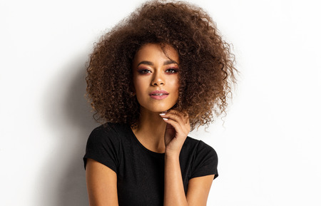 Beauty portrait of young adult african american woman with afro hairstyle looking at camera isolated on white backgroundの写真素材