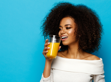 Beautiful african american girl with copy space drinking a orange juiceの写真素材