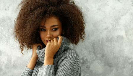 Portrait of young black woman with an afro hair wear high-neck wool and cashmere sweaterの写真素材
