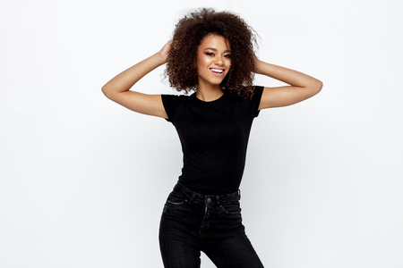 Beautiful smiling african american woman with an afro hairstyle wearing black clothes and looking at camera isolated on whiteの写真素材
