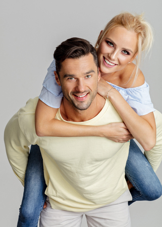 Young smiling man piggyback his beautiful girlfriendの写真素材