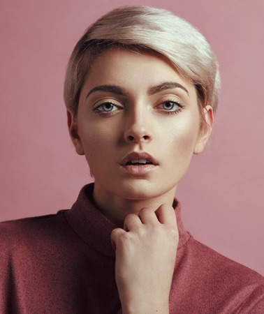 Portrait of fashion woman with blond short hair isolated on pink backgroundの写真素材