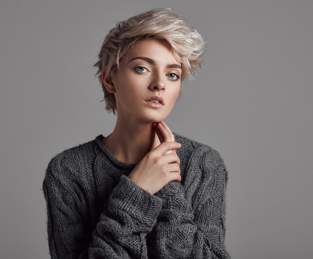 Fashion portrait of young woman with blond short hair isoalted on gray backgroundの写真素材