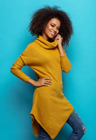 Beautiful african american woman with afro wearing cardigan and looking at cameraの写真素材