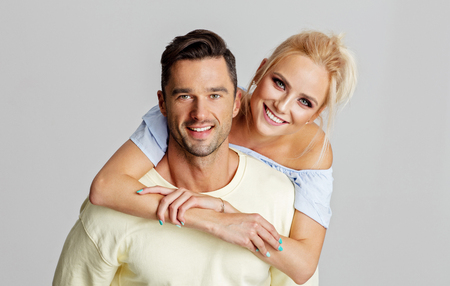 Young adult couple smiling and lookig at camera isolated on gray backgroundの写真素材