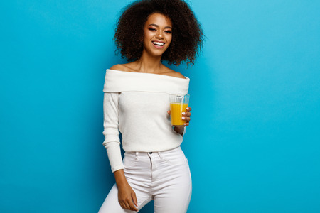 Beautiful smiling african american girl with a glass of orange juiceの写真素材