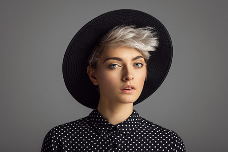 Beautiful glamour portrait of young woman wearing black hat and polka dots shirtの写真素材