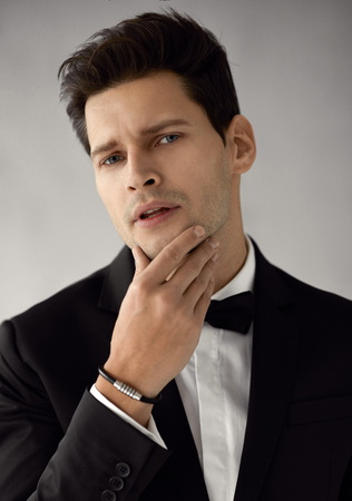 Portrait of handsome man in black suit touching a beardの写真素材