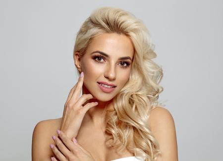 Blond bautiful woman touching her cheek isolated on gray backgroundの写真素材