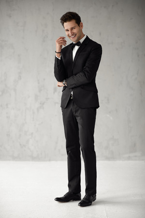 Handsome smiling man in black suit looking at cameraの写真素材