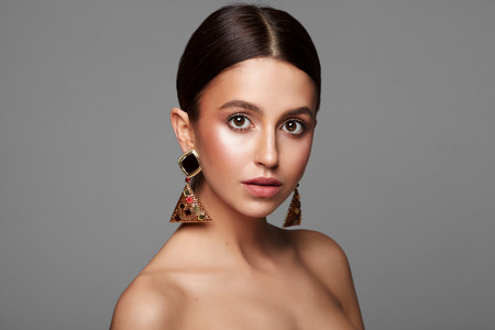 Portrait of female moel with earrings isolated on gray backgroundの写真素材