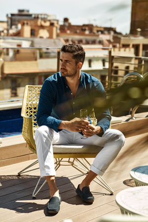 Handsome model relaxing and drinking white wineの写真素材