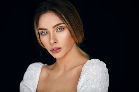 Close-up portrait of blonde woman looking at camera and isolated on black backgroundの写真素材