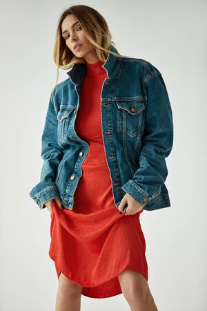 Fashion photo of female blonde model wear blue denim jacket and red dress. High fashion.の写真素材