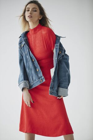 Fashion photo of blonde sexy woman in stylish dress and denim jacket posing in photo studioの写真素材