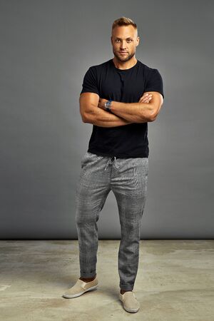 Handsome man posing with watch and looking at camera, isolated on gray backgroundの写真素材