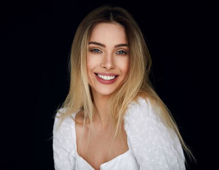 Portrait of smiling blonde woman looking at camera and isolated on black backgroundの写真素材