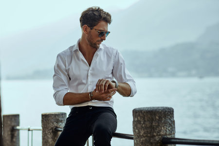 Stylish man in white shirt checking the time over the mountains backgroundの写真素材