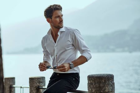 Stylish man in white classic shirt, looking at the mountains viewの写真素材