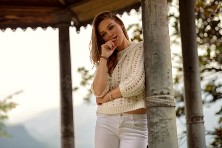 Beautiful young woman in wool sweater touching lips and thinking