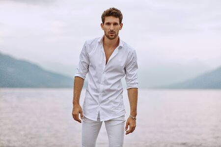 Handsome male model posing on a background of lake and mountainsの写真素材
