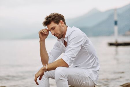 Handsome male model thinking outdoor on a background of lake and mountainsの写真素材