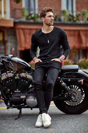 Handsome man in black sitting on american classic motorbikeの写真素材