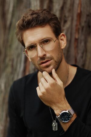 Portrait of handsome man wear glasses and watch on left hand looking at cameraの写真素材