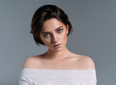 Studio shoot of young sensual brunette woman with short hair isolated on gray backgroundの写真素材