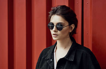 Portrait of a young woman in sunglasses over red backgroundの写真素材