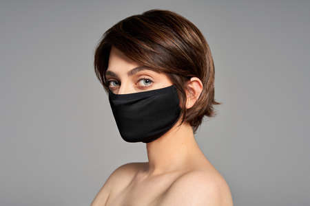 Close-up portrait of girl with protection flu cold facial mask isolated over gray backgroundの写真素材