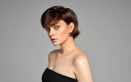 Beautiful woman with clean skin, natural make-up, and short hair on gray backgroundの写真素材