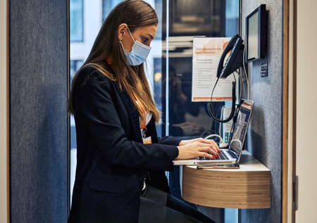 Businesswoman working on laptop and wearing face masks protect from coronavirus in officeの写真素材