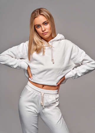 Beautiful sexy blonde woman wear of white set of tracksuit isolated on gray backgroundの写真素材