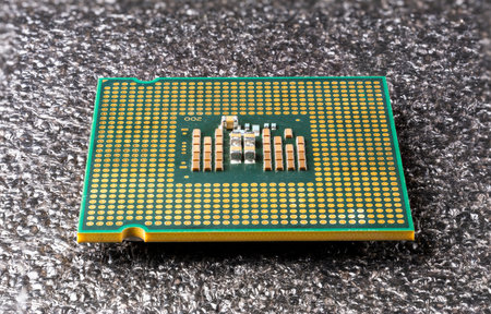 Old computer processor lies upside down on a black soft pad.